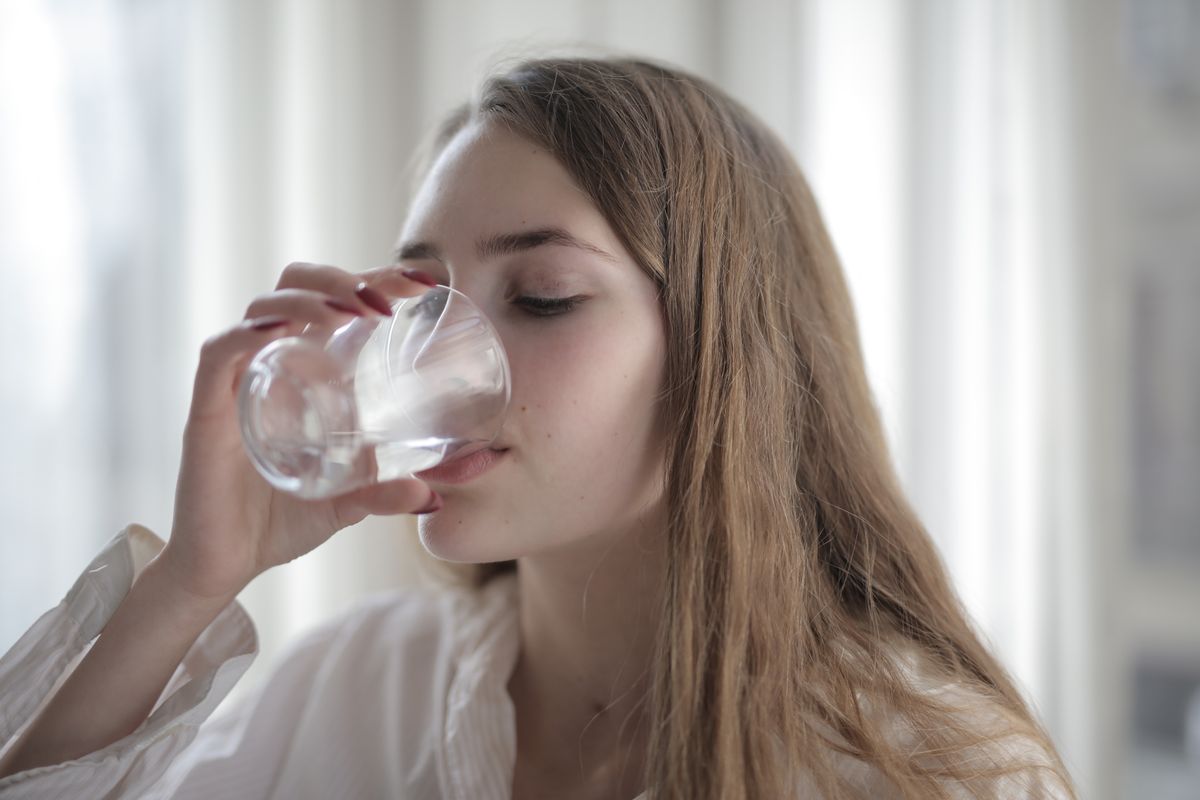 Persona bebiendo agua a sorbos sin pajita después de la extracción de una muela del juicio