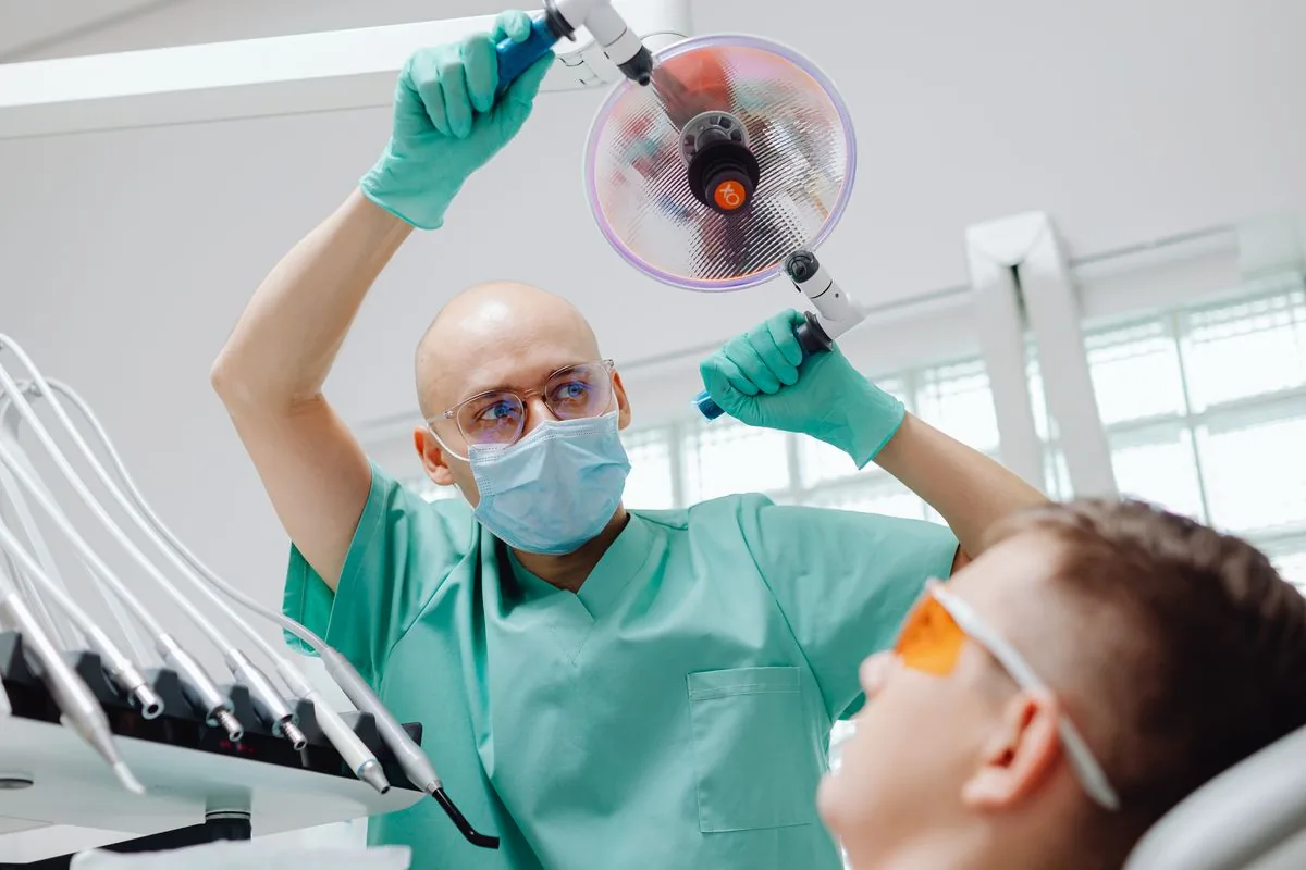 Odontólogo preparando la cura de una alveolitis seca con el paciente reclinado en el sillón dental