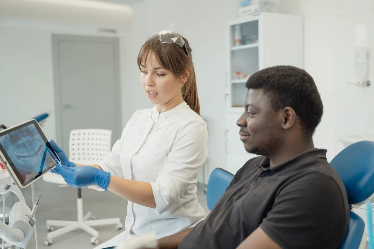 Dentista revisando con el paciente la radiografía para diagnosticar un bulto en la encía