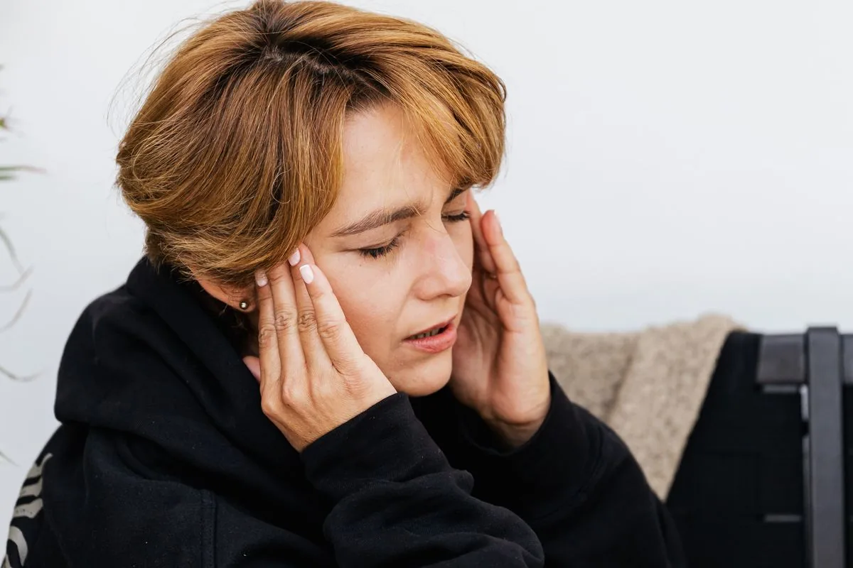 Mujer con dolor de alveolitis seca que se irradia hacia el oído y la sien