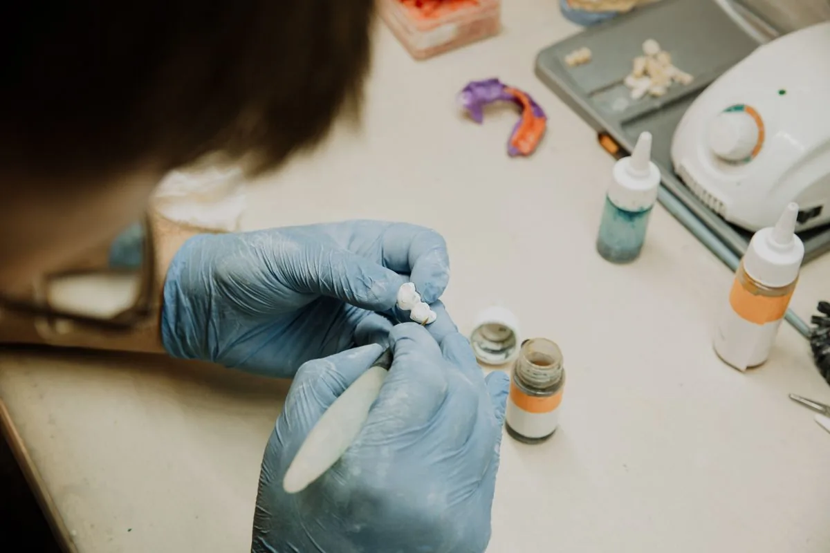 Técnico dental fabricando las piezas cerámicas de un puente o una corona sobre implante