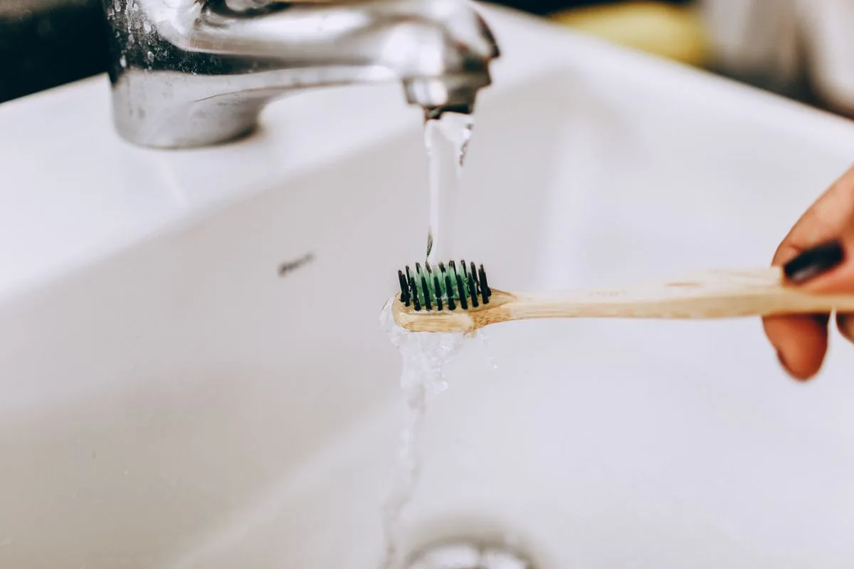 Cepillo de cerdas suaves bajo el grifo para la limpieza del retenedor removible con agua fría