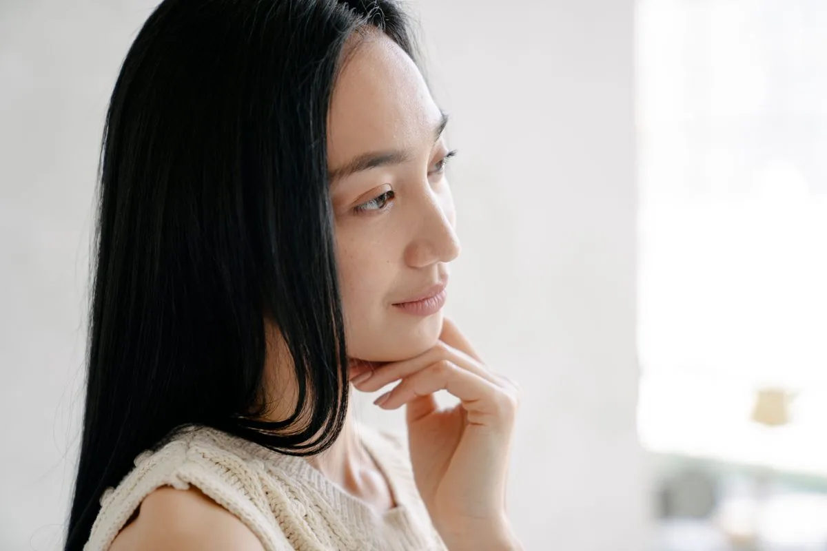 Mujer tocándose el mentón y el labio inferior para comprobar la sensibilidad tras la extracción de la muela del juicio