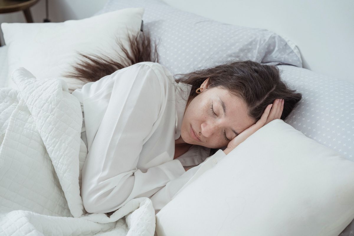 Mujer descansando con la cabeza sobre almohadas para reducir el dolor después de la extracción de una muela del juicio