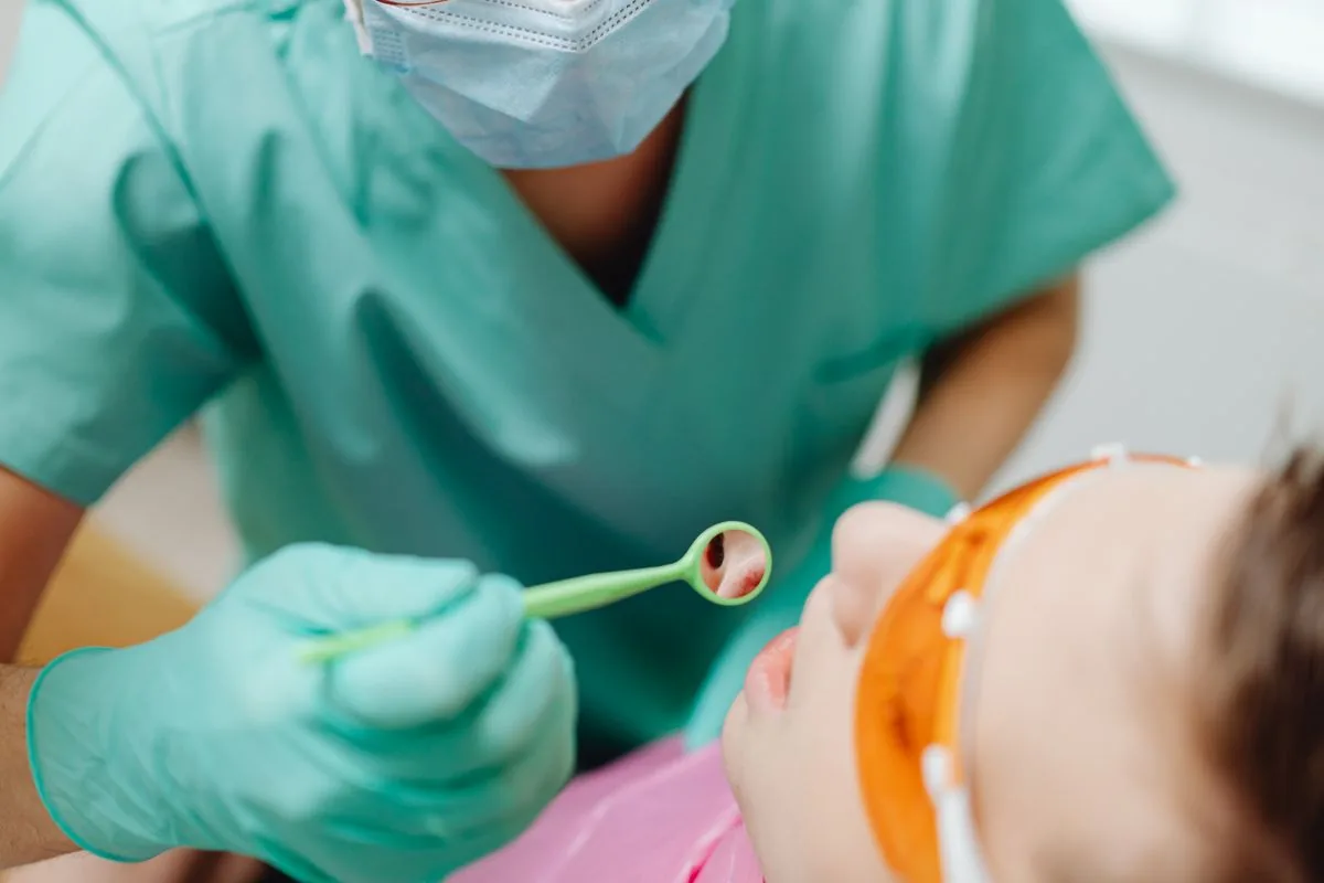 Odontopediatra revisando a un niño con espejo dental durante el control de su mantenedor de espacio